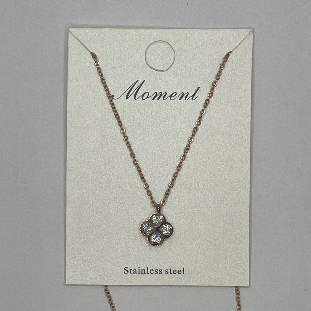A stainless steel necklace with a clover-shaped pendant, displayed on a card with the word 'Moment' written on it.